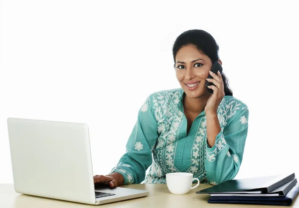 Mulher usando um laptop e um telefone celular — Fotografia de Stock