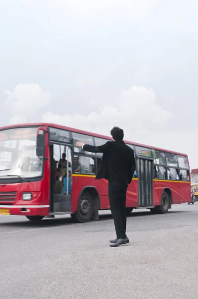 Businessman hailing bus at roadside — ストック写真