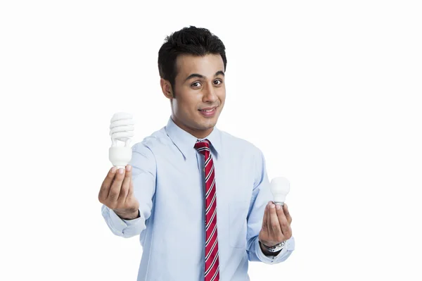Omul de afaceri compară un bec cu un bec eficient energetic — Fotografie, imagine de stoc