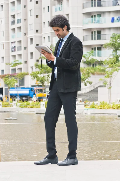 Uomo d'affari che utilizza un tablet digitale a bordo piscina — Foto Stock