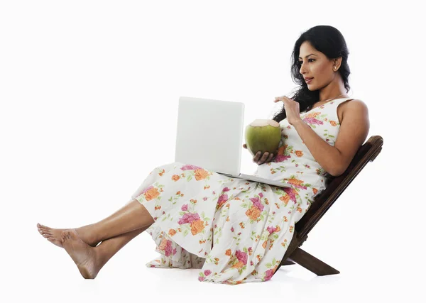 女人喝椰子牛奶和使用一台笔记本电脑 — 图库照片