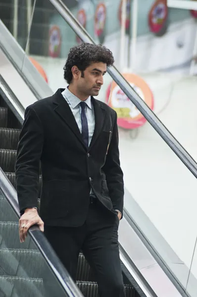 Businessman moving down on an escalator — Stock Photo, Image