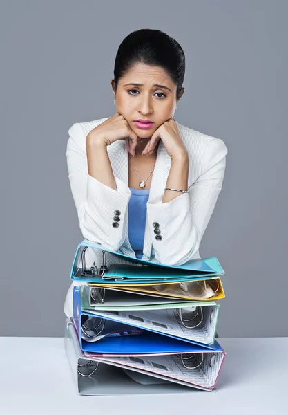 Businesswoman leaning on a stack of files — Stock Photo, Image