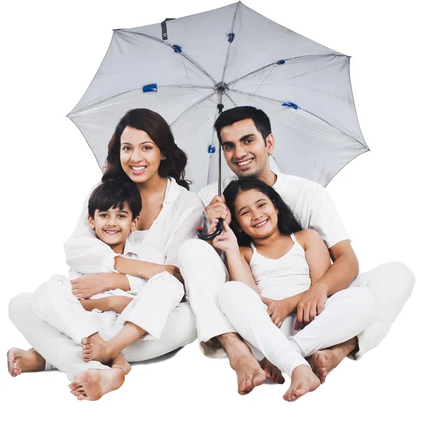Family sitting under an umbrella — Stock Photo, Image