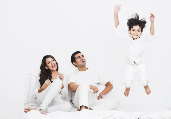 Jongen springen op het bed met zijn ouders — Stockfoto