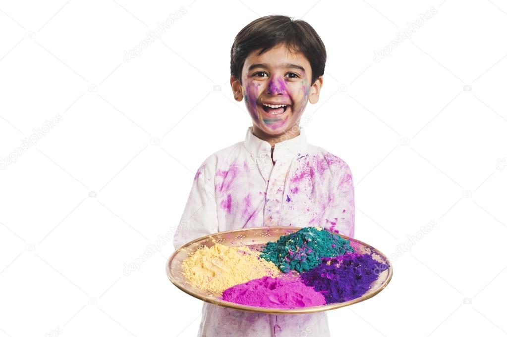 Boy holding Holi colors in a plate