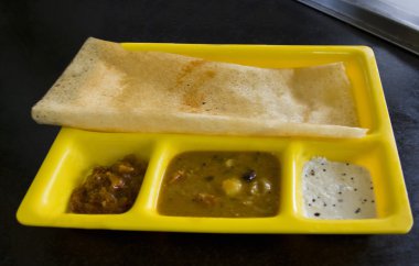 Dosa with chutneys and sambhar on a restaurant table clipart