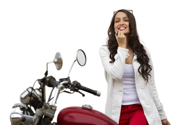 Mujer de pie junto a una motocicleta — Foto de Stock