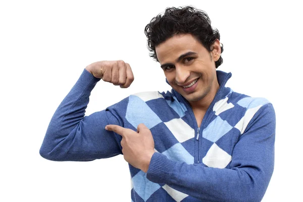 Smiling man pointing to his muscles — Stock Photo, Image