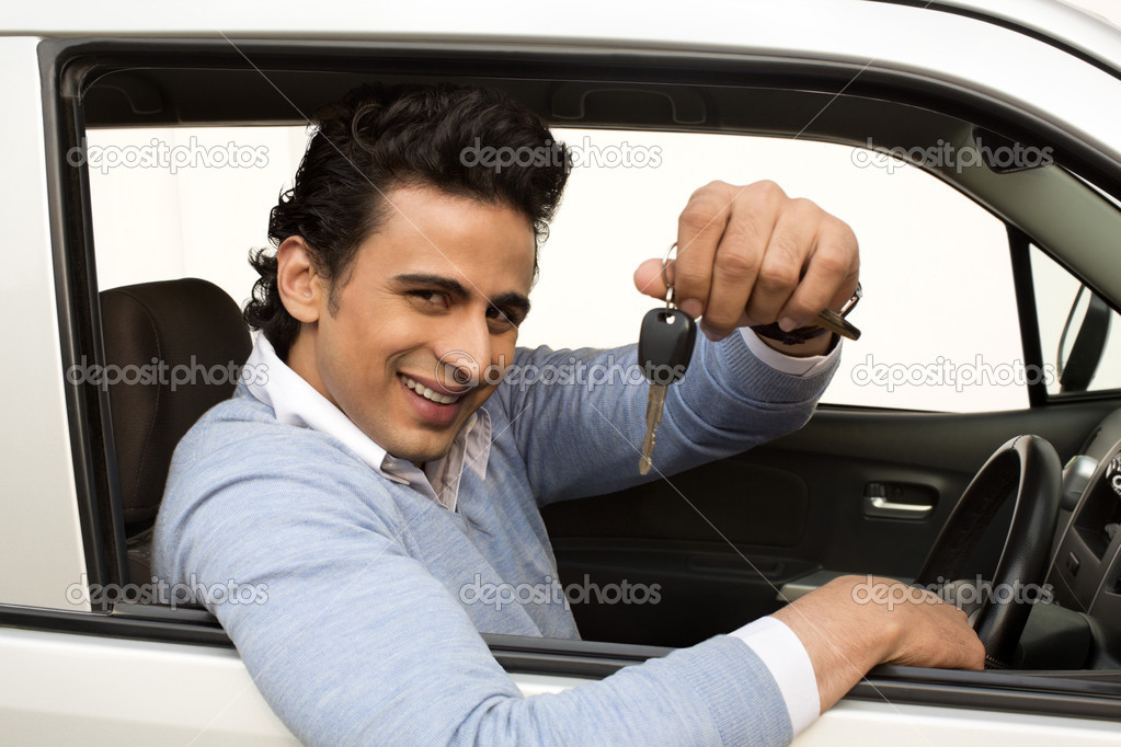 Smiling man sitting in a car and showing car key