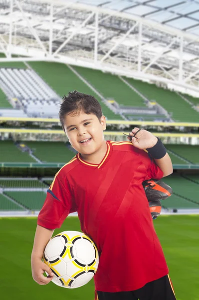 Niño llevando una pelota de fútbol y sus zapatos — Foto de Stock