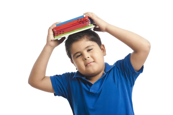 Boy holding a stack of books over his head — Stock Photo, Image