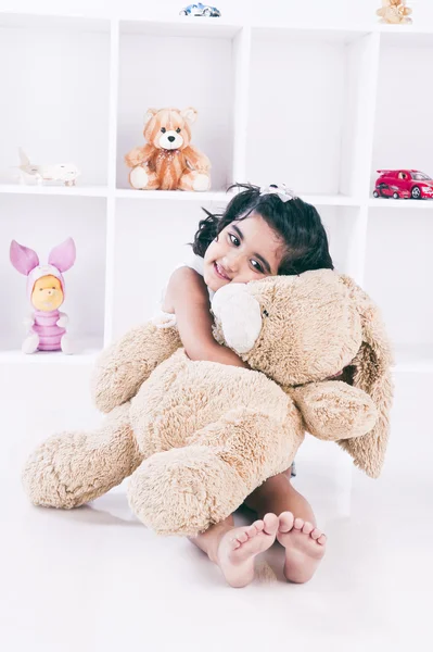 Chica sosteniendo un oso de peluche y sonriendo — Foto de Stock
