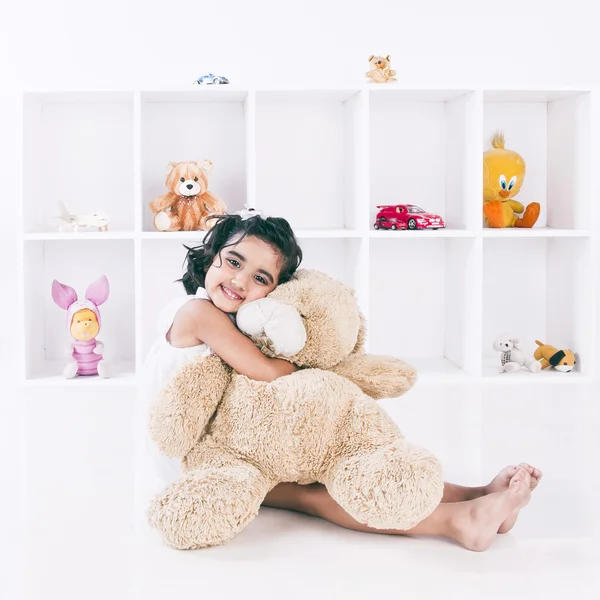 Retrato de uma menina segurando um ursinho de pelúcia e sorrindo — Fotografia de Stock