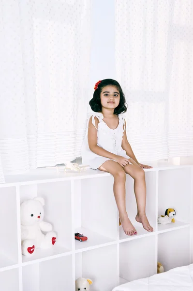 Retrato de uma menina sentada em uma prateleira — Fotografia de Stock