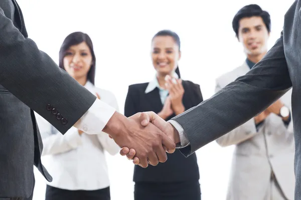 Dos hombres de negocios estrechando la mano con sus colegas aplaudiendo — Foto de Stock