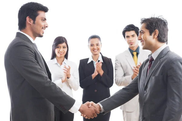 Dos hombres de negocios estrechando la mano con sus colegas aplaudiendo —  Fotos de Stock