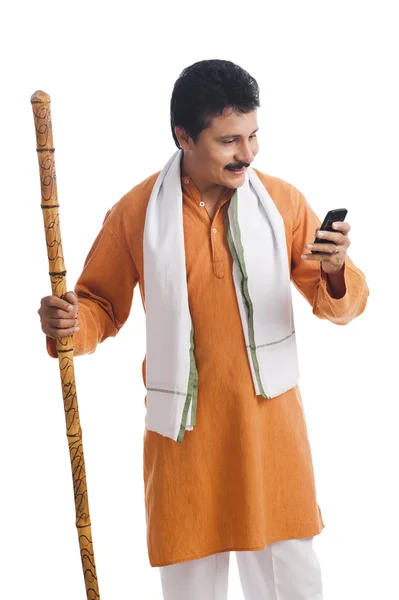 Hombre sosteniendo un bastón de madera y usando un teléfono móvil —  Fotos de Stock