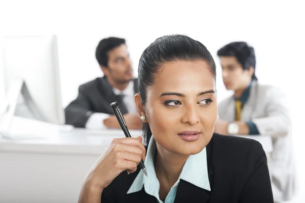 Primer plano de una mujer de negocios sosteniendo una pluma con sus colegas en el fondo —  Fotos de Stock