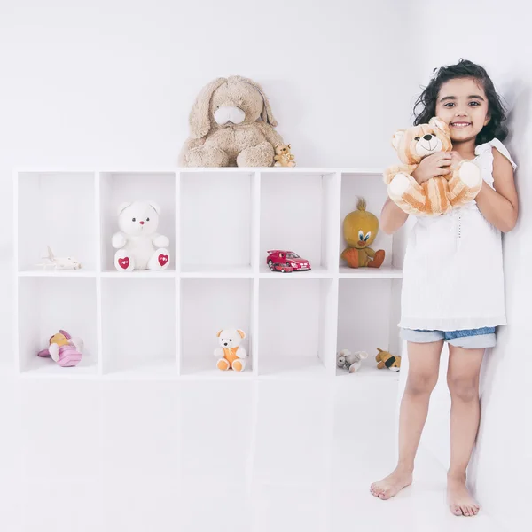 Retrato de uma menina segurando um ursinho de pelúcia e sorrindo — Fotografia de Stock