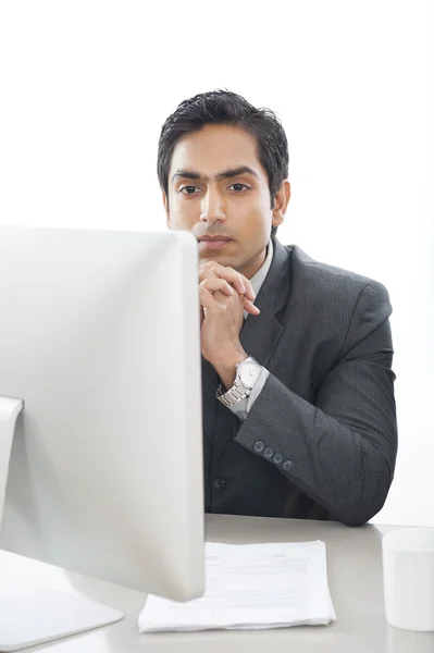Geschäftsmann sitzt vor dem Computer und denkt nach — Stockfoto