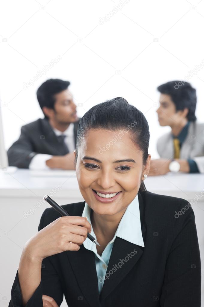 Businesswoman smiling in an office with their colleagues in the background