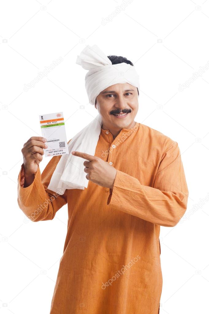 Portrait of a man pointing at an Aadhaar Card and smiling