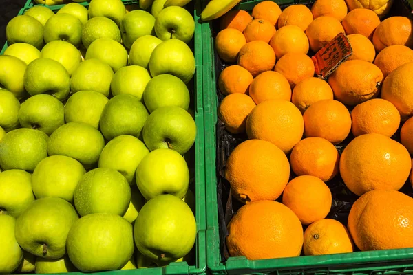 Jablka Granny smith a pomeranče v bednách na prodej za značku — Stock fotografie