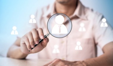 HRM ya da İnsan Kaynakları Yönetimi araştırması. İş adamı simgesine büyüteç kullanmak. İşe alım ya da insan gelişimi kavramı için.