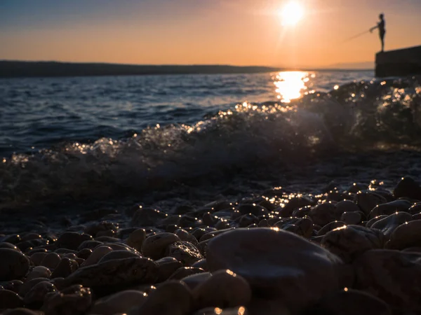 夏天日落后 在水中看到石子和卵石的神秘景象 背景中的一个垂钓者的轮廓 — 图库照片