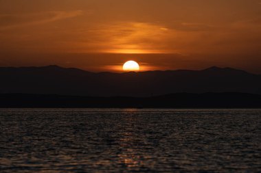 Hırvatistan 'da güneş bir kıyı sıradağının üzerinde batıyor.