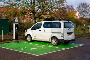 Woodbridge Suffolk UK 28 Kasım 2021: Nissan E-NV200 elektrikli minibüs Suffolk, İngiltere 'de halka açık bir otoparkta şarj ediliyor