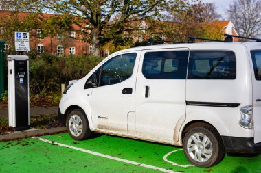 Woodbridge Suffolk UK 28 Kasım 2021: Nissan E-NV200 elektrikli minibüs Suffolk, İngiltere 'de halka açık bir otoparkta şarj ediliyor