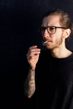 Woodbridge Suffolk UK Mayıs 08 2020: El yapımı sigara veya esrar içen genç bir erkek hippi