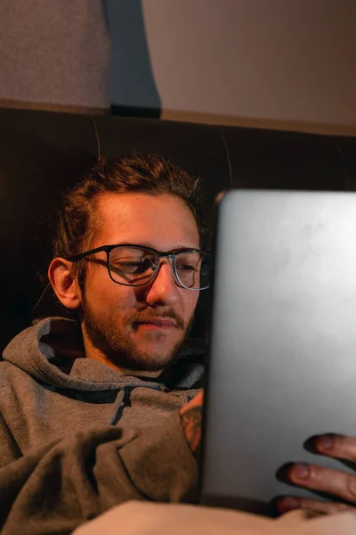 Yatmadan önce tablet kullanan genç bir adam. Bağımlılık, sosyal medya, karanlık kavramdan sonra, kitap