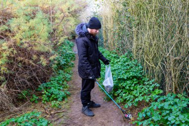 Bawdsey, Suffolk, İngiltere Ocak 06: 2021: Yetişkin bir erkek plajı temizliyor ve çöp topluyor. Çöp toplama, çevre, plaj temizliği