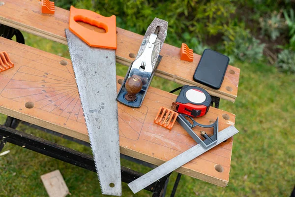 Üzerinde testere, mezura ve işaret de dahil olmak üzere çeşitli aletler bulunan bir tezgah. DIY, inşaat, ev geliştirme konsepti