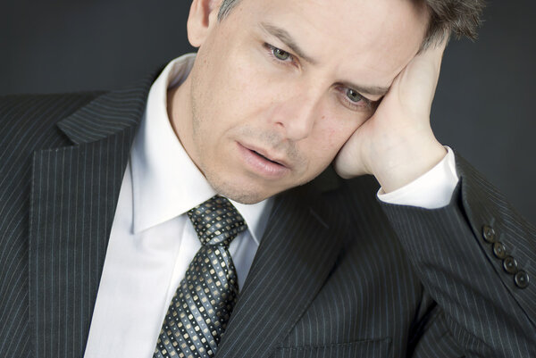 Defeated Businessman Looks Down While Holding Head In Hand