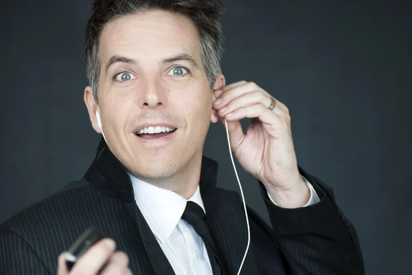 Lachende zakenman kijkt naar camera zoals hij het stelt op koptelefoon — Stockfoto
