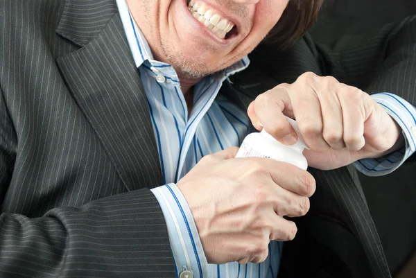 Homme d'affaires frustré essayant d'ouvrir la bouteille pilule — Photo