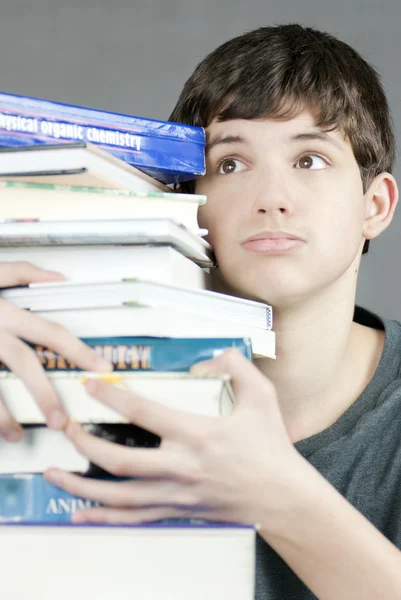 Adolescente impressionado detém pilha de livros didáticos — Fotografia de Stock