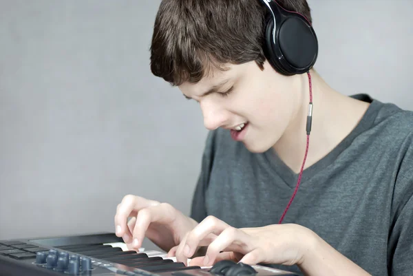 Kopfhörer tragender Teenager spielt Keyboard — Stockfoto