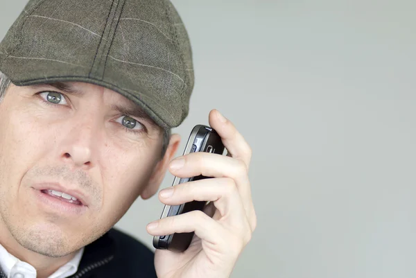 Стресс человек в шляпе газетчика на телефоне — стоковое фото
