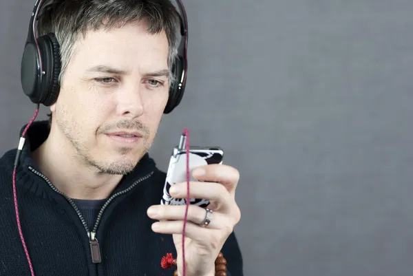 Kopfhörer tragender Mann schaut auf mp3-Player — Stockfoto