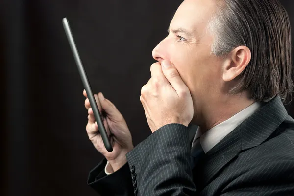 Geschäftsmann blickt erstaunt auf sein Tablet — Stockfoto