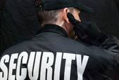 biztonsági őr figyel fülhallgató, vissza a kabát mutatja
