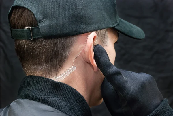 Guarda de segurança ouve fone de ouvido, por cima do ombro — Fotografia de Stock