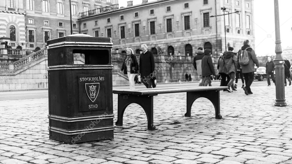 An empty bench and a trash can in front of the Royal Palace in black and white