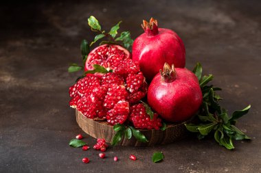 Olgun nar. Koyu arkaplandaki tahtanın üzerinde yapraklar var.