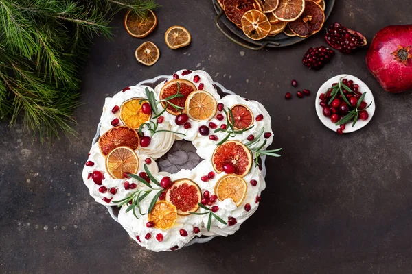 Meringues pavlova cake wreath with whipped cream, pomegranate and orange